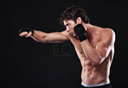 Photo for Fitness, boxing and man punching in studio for exercise, challenge or competition training for gym. Power, muscle or serious champion boxer at mma workout with confidence, fight and black background. - Royalty Free Image