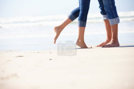 Photo for Couple, beach and love by feet in nature with hug, romance or fun adventure closeup. Legs, zoom or people at ocean for travel, freedom and bonding on sea journey for anniversary, date or honeymoon. - Royalty Free Image