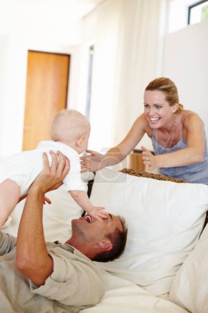 Photo for Funny, happy family and play with baby on sofa in home for love, care or father bonding together with mother. Dad, kid and cute infant in living room for connection, smile or parents laugh with child. - Royalty Free Image