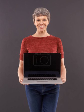 Photo for Elderly, woman and laptop screen in studio with smile, technology and online search or typing and internet connection. Information, browse or social network, senior female person on mockup background. - Royalty Free Image