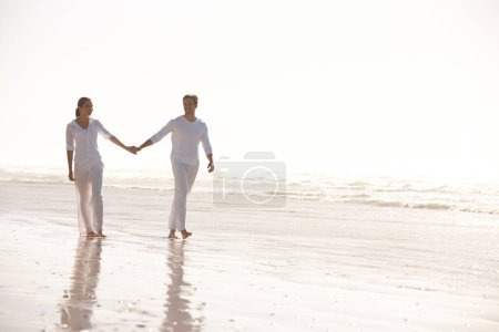 Photo for Couple, sea and holding hands while walking on beach, travel and commitment with trust and bonding outdoor. Love, care and support in relationship, honeymoon or anniversary with peace in nature. - Royalty Free Image