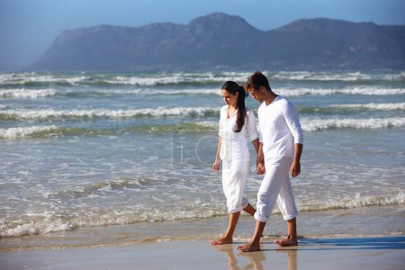 Photo for Couple, holding hands and walking with love on beach for bonding, care or support in nature. Man and woman enjoying stroll by the ocean waves or coast for holiday, weekend or outdoor trip by the sea. - Royalty Free Image