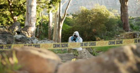 Photo for Csi, photographer and evidence at crime scene for investigation in forest with police tape and safety hazmat. Forensic quarantine, expert investigator and pictures for observation and case research. - Royalty Free Image