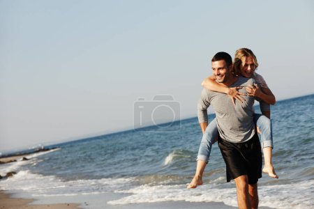 Téléchargez les photos : Couple, l'eau de mer et le piggyback en vacances, sourire et la paix à la plage ou le jeu par ciel bleu. Les gens, île heureuse et tropicale pour se lier le week-end, nature en plein air et amour pour le mariage ou la romance. - en image libre de droit