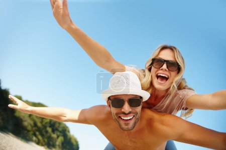 Téléchargez les photos : Couple, lunettes de soleil et piggyback en vacances, plaisir et paix à la plage ou jeu par ciel bleu. Les gens, île heureuse et tropicale pour se lier le week-end, nature en plein air et amour pour le mariage ou la romance. - en image libre de droit