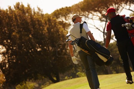 Photo for Men, golf course and walking for sports, game challenge and exercise for hobby in summer travel outdoor. Golfer or friends and talk with equipment for recreation and activity for fun on vacation. - Royalty Free Image