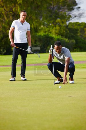 Photo for Men, play and aim golf ball at hole for sport, fitness or health in outdoor competition on summer day. People, watch and concentrate in tournament on green course for drive, hit and putt together. - Royalty Free Image