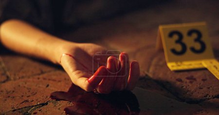 Photo for Victim, hand and blood on ground at crime scene with tag, sign and warning for investigation in closeup. Person, sidewalk and metro street for forensic inspection for murder, homicide and emergency. - Royalty Free Image