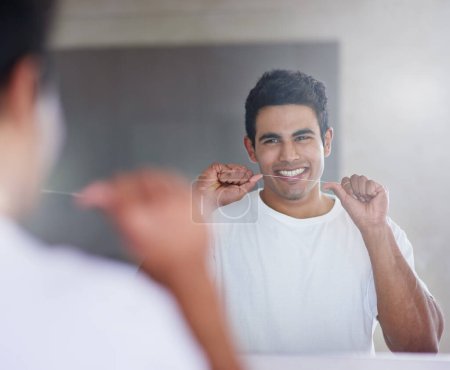 Smile, mirror and man with floss in bathroom for dental hygiene, gum disease and oral care. Health, happy and person in reflection after brushing teeth for wellness, cleaning and fresh breath in home.