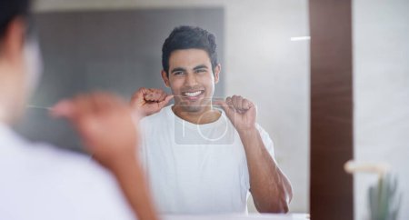Happy, mirror and man with floss in bathroom for dental hygiene, gum disease and oral care. Health, mouth and person in reflection after brushing teeth for wellness, cleaning and fresh breath in home.