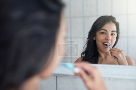 Photo for Brushing teeth, dental and hygiene with girl for healthcare, wellness and fresh by mirror in bathroom. Health, tooth whitening, gum care and cleaning mouth with woman as morning routine at home. - Royalty Free Image