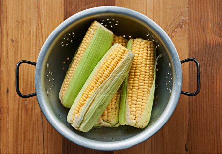 Photo for Closeup, corn or maize on table for fruit, wellness or healthy nutrition in home meal or kitchen. Cobs, background or above of natural produce for raw organic food, fiber or vitamin b in lunch diet. - Royalty Free Image