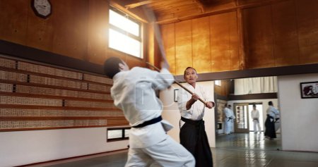 Aikido men, fight and bokken for martial arts, weapon or contest for black belt students at training, gym or dojo. Japanese people, wood sword and sensei for exercise, workout and fitness in battle.