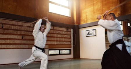 Téléchargez les photos : Homme d'Aïkido avec sensei, épée en bois et entraînement au combat en fitness, bataille ou action dans la salle de gym traditionnelle au Japon. Exercice, pratique et étudiant avec maître, ceinture noire et dojo d'arts martiaux japonais. - en image libre de droit