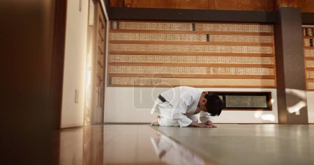 Téléchargez les photos : Étudiant japonais, arc ou homme en dojo pour commencer la pratique de l'aikido, la discipline ou l'éducation à l'autodéfense. Ceinture noire salutation maître, athlète apprendre le respect ou prêt dans la classe de combat ou l'entraînement seul. - en image libre de droit