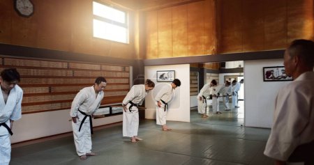 Téléchargez les photos : Étudiants japonais, arc ou sensei in dojo pour commencer la pratique de l'aikido, la discipline ou l'éducation à l'autodéfense. Maître ceinture noire, personnes apprenant le respect ou prêt pour le cours de combat, l'entraînement ou l'aikido. - en image libre de droit