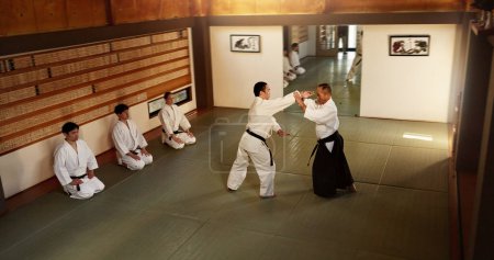 Photo for Japanese men, martial arts class or training in fight, modern or aikido to learn self defence. Sensei, black belt students and instruction in dojo place, sport and combat demonstration for discipline. - Royalty Free Image
