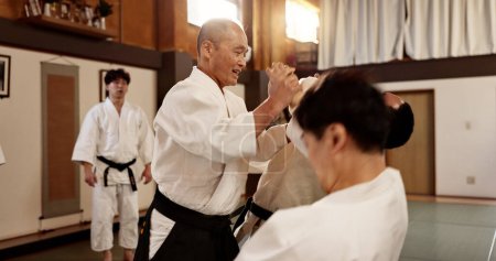 Photo for Aikido class, man and sensei for martial arts, learning and advice for combat at training, gym and dojo. Japanese people, master and sports with fight, workout and fitness for zen, conflict or club. - Royalty Free Image