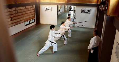 Photo for Aikido students, stick or learning martial arts in dojo for practice, movement or self defense. Combat demonstration, above or Japanese people in training workout for fighting, education or sensei. - Royalty Free Image