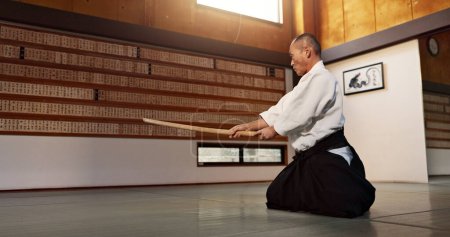 Téléchargez les photos : Aïkido avec sensei, épée en bois et entraînement pour la forme physique, le combat ou l'action dans la salle de gym traditionnelle au Japon. Exercice, pratique et homme mûr au dojo avec ceinture noire dans les arts martiaux japonais professionnels. - en image libre de droit