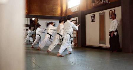 Téléchargez les photos : Aïkido, ceinture noire et cours de combat avec entraînement sensei ou enseignement aux athlètes pour l'exercice d'autodéfense. Dojo, les étudiants et les personnes dans un gymnase ou un studio pour l'entraînement, la pratique et la routine de remise en forme au Japon. - en image libre de droit