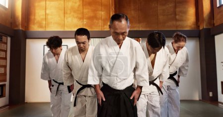 Photo for Japanese people, bow and respect in aikido in dojo place, training and modern martial arts class of self defence. Group, black belt students and sensei in honor and commitment in fighting discipline. - Royalty Free Image