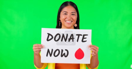 Photo for Asian woman, billboard and blood donation on green screen for advertising against a studio background. Portrait of happy female person with sign or poster in donate, healthcare or volunteer on mockup. - Royalty Free Image