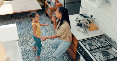 Photo for Mother, child and happy dance in kitchen with energy, fun and bonding for quality time together from above. Mom, young girl kid and singing in home for celebration, dancing and excited for music. - Royalty Free Image