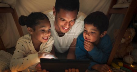 Téléchargez les photos : Nuit, père et enfants avec une tablette, des films en streaming et le bonheur avec des liens, la famille et l'amour ensemble. Soirée, parent masculin et les enfants avec la technologie, ludique et amusant avec des vidéos en ligne. - en image libre de droit