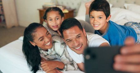 Photo for Selfie, phone and family together on bed for happy portrait, memory and social media post of bonding, quality time or weekend. Morning with dad, mom and children in bedroom waking up and relaxing. - Royalty Free Image