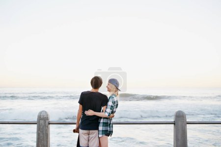 Photo for Couple, skateboard and happy on beach for love with mockup space, adventure or promenade date. Gen z skater, people and travel on boardwalk for bonding, embrace and outdoor fun with morning waves. - Royalty Free Image