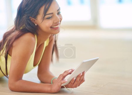 Téléchargez les photos : Jeune, femme et tablette sur le sol avec heureux pour la connectivité, streaming ou achats en ligne. Femme, technologie et sourire pour les médias sociaux, l'apprentissage en ligne et le jeu en chat ou en texto. - en image libre de droit