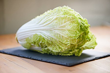 Photo for Whole vegetable, fresh and cutting board in kitchen for diet, cooking and wellness. Cabbage, green and natural produce for food, nutrition and vegan in house for salad leaves, food and gut health - Royalty Free Image