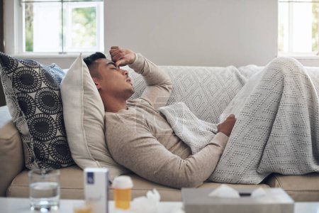 Photo for Sick man, headache and medication with flu, sinus or pain from illness on living room sofa at home. Tired male person with migraine from high fever, influenza or infection on lounge couch at house. - Royalty Free Image