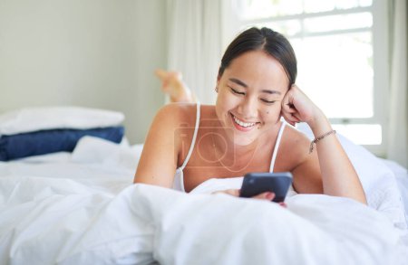 Woman, bed and scroll on phone or social media, internet and laugh for funny meme or joke in home. Happy female person, online and streaming news or gossip article, reading and ebook or app to chat.