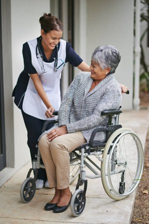 Photo for Senior woman and wheelchair at nursing home with nurse for assistance with disability, help at clinic. Disabled patient or medical or outdoors for talk or plan for healthcare, conversation with carer. - Royalty Free Image