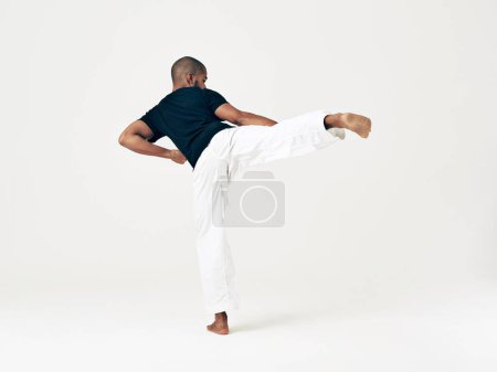Foto de Hombre, estudio y artes marciales para la práctica de patadas, acción y ejercicio de karate sobre fondo blanco. Hombre negro, espacio de maqueta y entrenamiento para combate, espalda y posición de ataque en taekwondo. - Imagen libre de derechos
