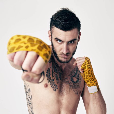 Photo for Man, fight swing and punch for martial arts, self defense and fitness for physical strength and exercise in studio. Angry man, glove bandage and portrait for combat and recreation sport with fist. - Royalty Free Image