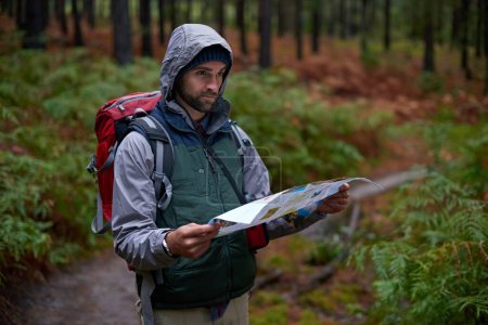 Photo for Search, map and man lost in forest with guide to camp in woods or thinking of navigation or direction. Confused, travel and trekking in nature with backpack or plan to find location on hiking journey. - Royalty Free Image