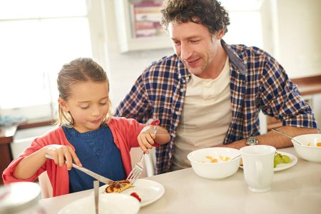 Photo for Father, girl and breakfast in house kitchen for teaching, pancakes and nutrition with plate, knife and fork. Dad, kid and brunch in home at morning for learning, coffee and health with fruit by table. - Royalty Free Image