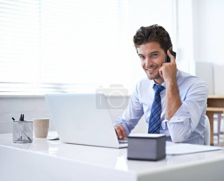 Foto de Claro, podemos hacer eso por ti. Un joven hombre de negocios hablando por teléfono sentado en su escritorio - Imagen libre de derechos