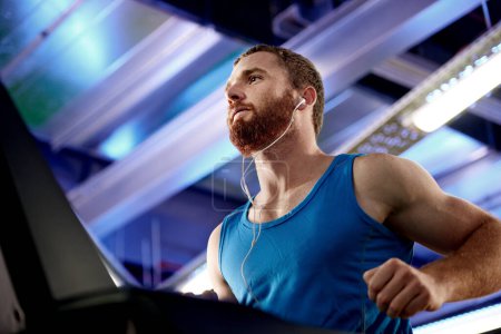 Photo for Earphones, fitness and man running on treadmill in gym for health, wellness and body weight loss. Exercise, runner and male athlete with cardio workout on machine for race training in sports center - Royalty Free Image