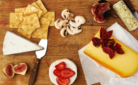 Photo for Fruit, cheese and knife on kitchen table for food with appetizer, healthy eating and gourmet snack. Charcuterie board, wellness and strawberry on wood surface with brunch, mushrooms and fine dining. - Royalty Free Image