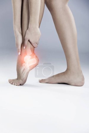 Téléchargez les photos : Cheville, douleur et blessure d'urgence au pied avec inflammation due à l'arthrite ou à l'ostéoporose en studio. Médical, traumatisme et rayons X lueur sur les jambes de la personne avec tendinite dans les pieds, la goutte dans les articulations ou en crise. - en image libre de droit
