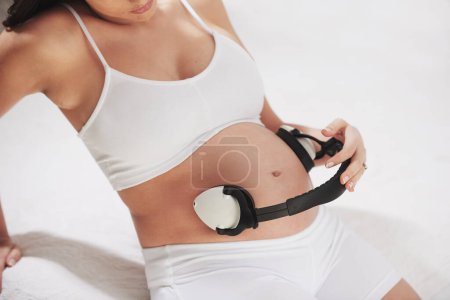 Photo for Pregnant, stomach and listening to music with headphones so baby relax to sound in womb for brain development. Pregnancy, belly and streaming audio to calm fetus with lullaby in home with mother. - Royalty Free Image