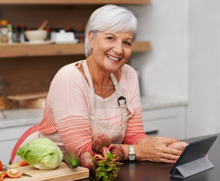 Photo for Portrait, old woman and online for cooking and tablet in kitchen and watch for learning, meal prep and guide. House, senior and female person in home, healthy and food, salad and recipe, video or app. - Royalty Free Image