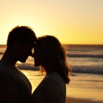 Couple, love and kiss at ocean with silhouette for date or summer holiday and bonding in Florida. Relationship, commitment and romance together as soulmate with smile, happy and vacation or honeymoon.