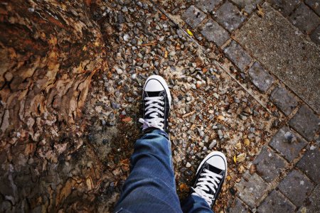 Photo for Pov, sneakers and person in city with fashion, casual style and trendy shoes on road, sidewalk or street. Top view, streetwear and feet of teen in town for travel, journey and adventure on weekend. - Royalty Free Image