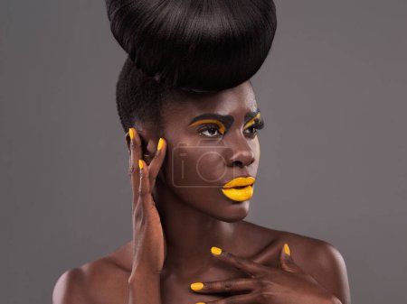 Photo for African, model and studio artistic with makeup, beauty and creative yellow lipstick. Bold, woman and skin with confidence, dramatic hair and bun for glamour and trendy cosmetics on grey background. - Royalty Free Image