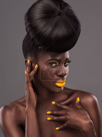 Photo for African, model and studio cool with makeup, beauty and creative yellow lipstick. Bold, woman and skin with confidence, dramatic hair and bun for glamour and trendy cosmetics on grey background. - Royalty Free Image